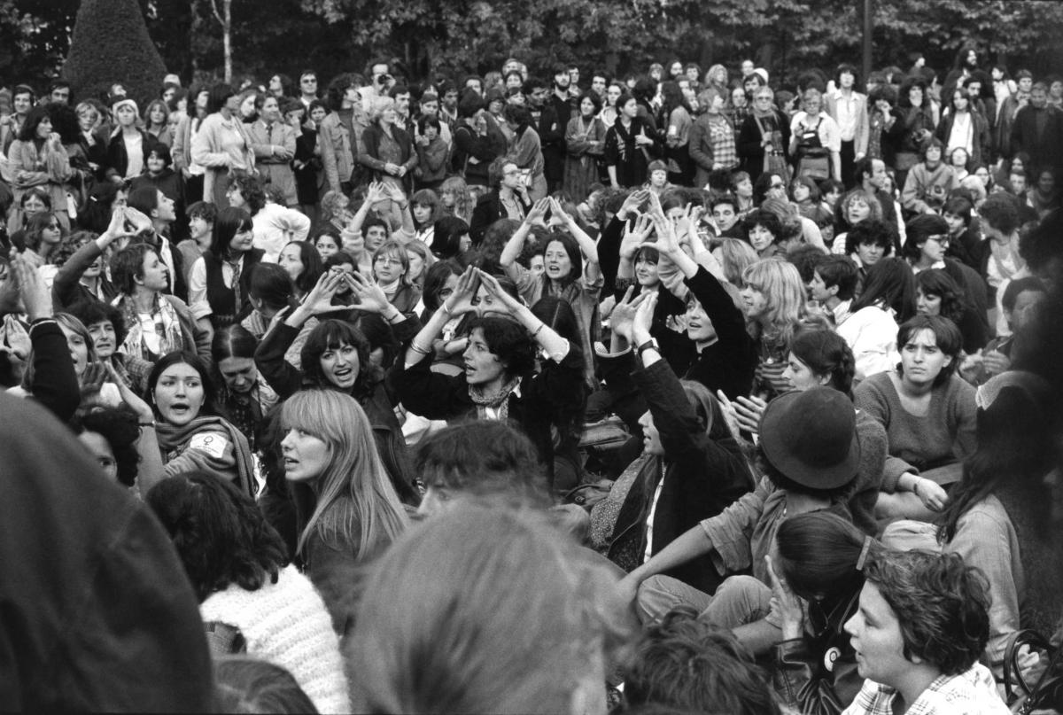 Marche des femmes, Groupe de femmes assises faisant le signe « féministe ».
