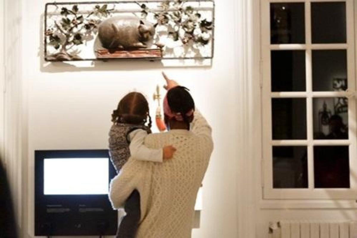 un parent montre pointe du doigt une enseigne à son enfant qu'il porte dans les bras