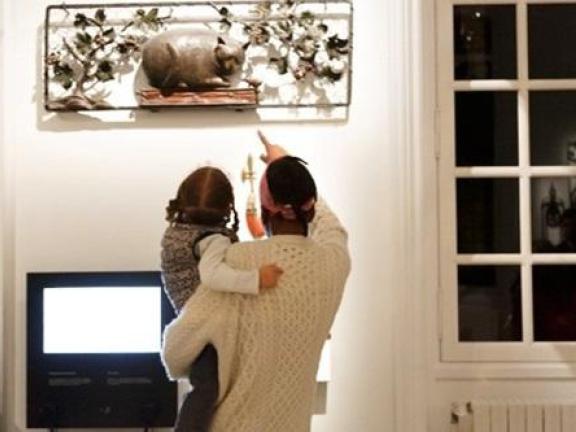 un parent montre pointe du doigt une enseigne à son enfant qu'il porte dans les bras